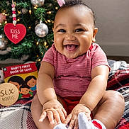 Laviarus joined the competition — help win amazing prizes! baby, book, child, christmas_tree, cute, decorations, festive, happy, holiday, indoor, infant, lights, ornaments, person, plaid_blanket, red_clothing, sitting, smiling, sock, toy