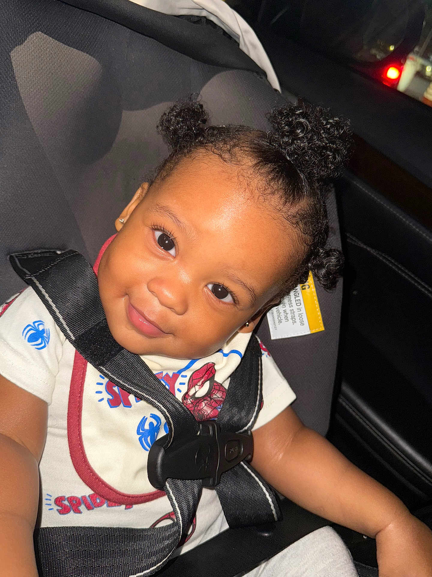 Mateo is registered to the contest to win money with this photo: toddler, child, car_seat, seatbelt, smile, curly_hair, hairstyle, clothing, spiderman, indoor, car_interior, cute, happy, portrait, baby, person, black_hair, seat, young_child, safety