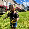 child, toddler, outdoor, lawn, grass, house, mobile_home, sunlight, blue_sky, clouds, flowers, flower_bush, grill, barbecue, atv, vehicle, car, beaded_hair, colorful_clothing, portrait