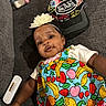 Gianna is registered to the contest to win money with this photo: baby, infant, child, portrait, lying_down, couch, flower_headband, colorful_clothing, fruit_pattern, dress, smiling, wide_eyed, indoor, home, furniture, pacifier, cap, baby_items, textile, photography
