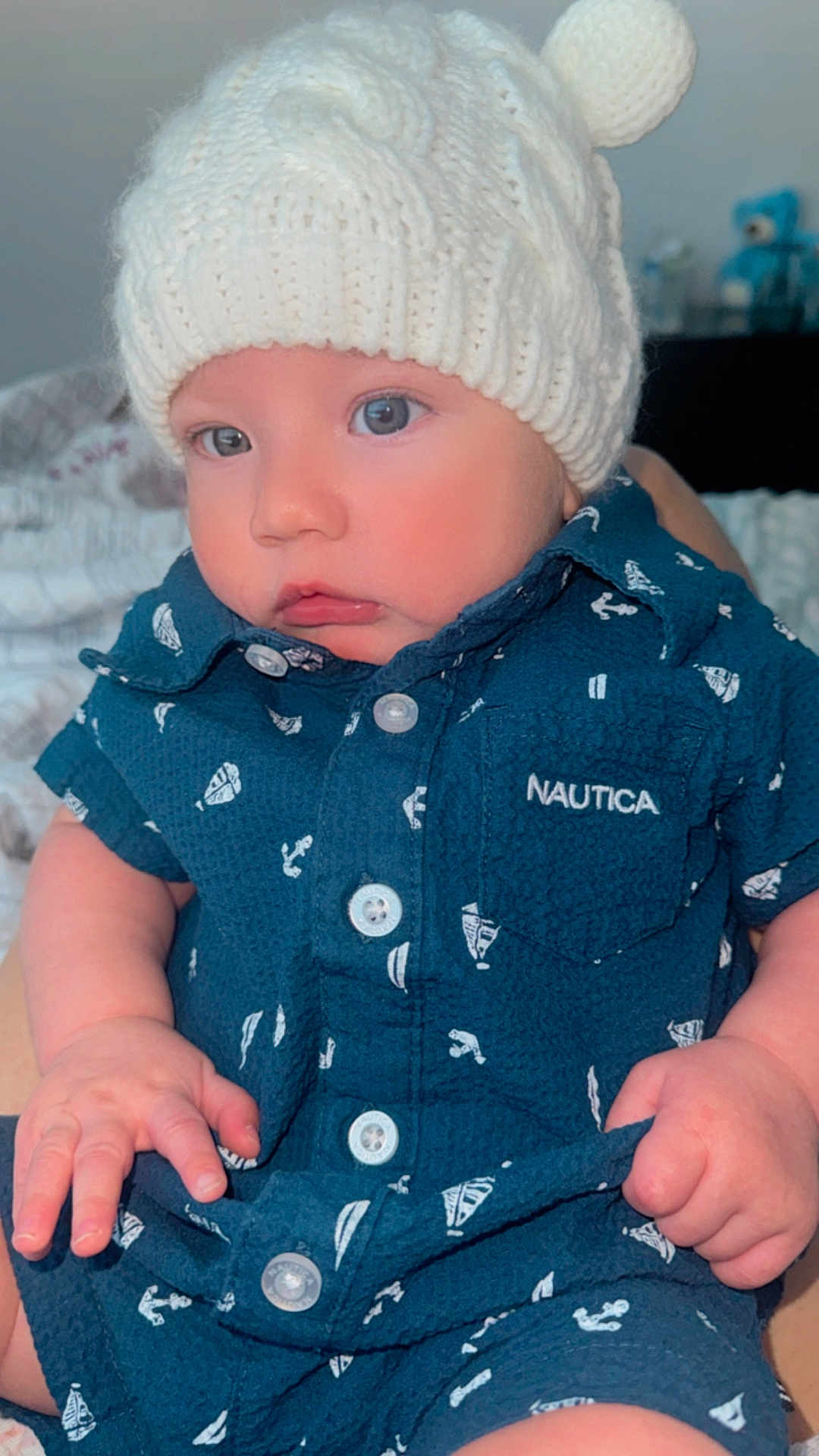 Emyr Gael is registered to the contest to win money with this photo: baby, infant, child, knit_hat, pom_pom, navy_blue, nautica, clothing, cute, portrait, indoor, soft_light, hands, face, eyes, sitting, fabric, cozy, closeup, expression