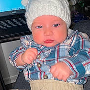 Emyr Gael joined the competition — help win amazing prizes! baby, child, infant, knit_hat, plaid_shirt, beige_pants, fist, face, blue_eyes, indoor, laptop, technology, table, photograph, person, portrait, clothing, cute, expression, hat