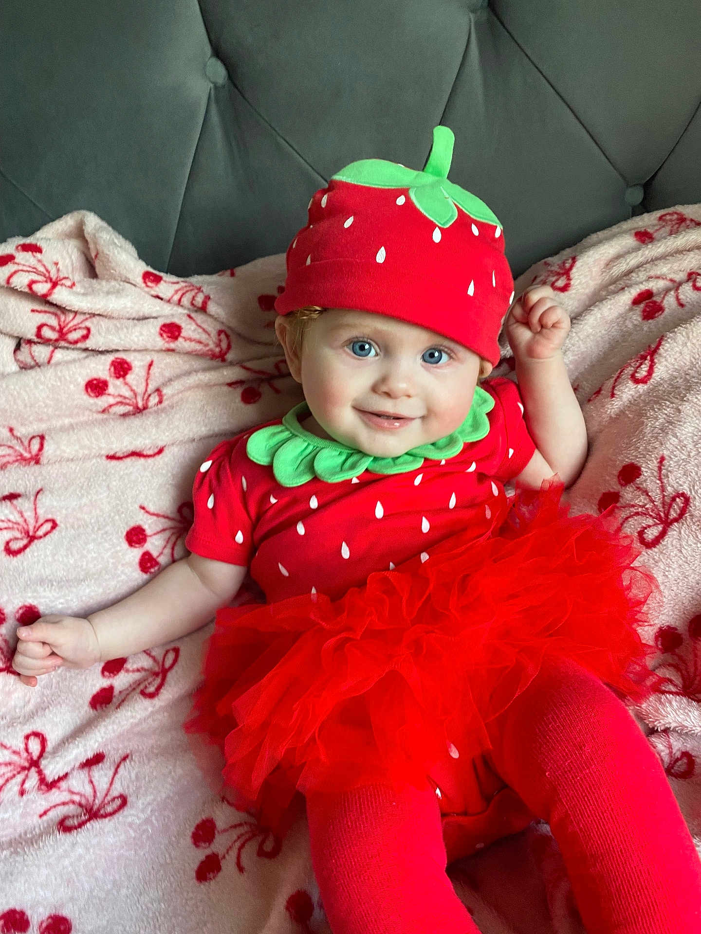 Nova is registered to the contest to win money with this photo: baby, child, smiling, tutu, hat, red_clothing, blue_eyes, blanket, cherry_pattern, costume, cute, portrait, sitting, indoors, soft_fabric, person, headwear, infant, happy, cozy
