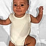 baby, infant, onesie, smile, face, arms, legs, skin, lying_down, blanket, white_clothing, cute, child, happy, portrait, young_child, baby_skin, small_hands, small_feet, indoors