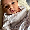baby, infant, close_up, face, tongue_out, white_clothing, blanket, blue_polka_dots, hand, soft_lighting, indoors, cute, newborn, person, skin, expression, head, eyes, wrinkled_clothing, cozy