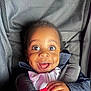 child, toddler, smiling, car_seat, happy, face, close_up, dimples, clothing, seatbelt, infant, portrait, baby, young_child, cute, person, expression, indoors, joyful, bright_eyes