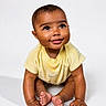 baby, child, smiling, cute, yellow_clothing, sitting, hands, feet, portrait, happy, infant, closeup, studio, expression, skin, eyes, face, one_person, isolated, background