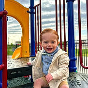 Charlie joined the competition — help win amazing prizes! toddler, child, playground, slide, smiling, happy, blue_eyes, bow_tie, jacket, shorts, sneakers, outdoor, play_equipment, daylight, cloudy_sky, fence, metal, plastic, fun, casual_clothing