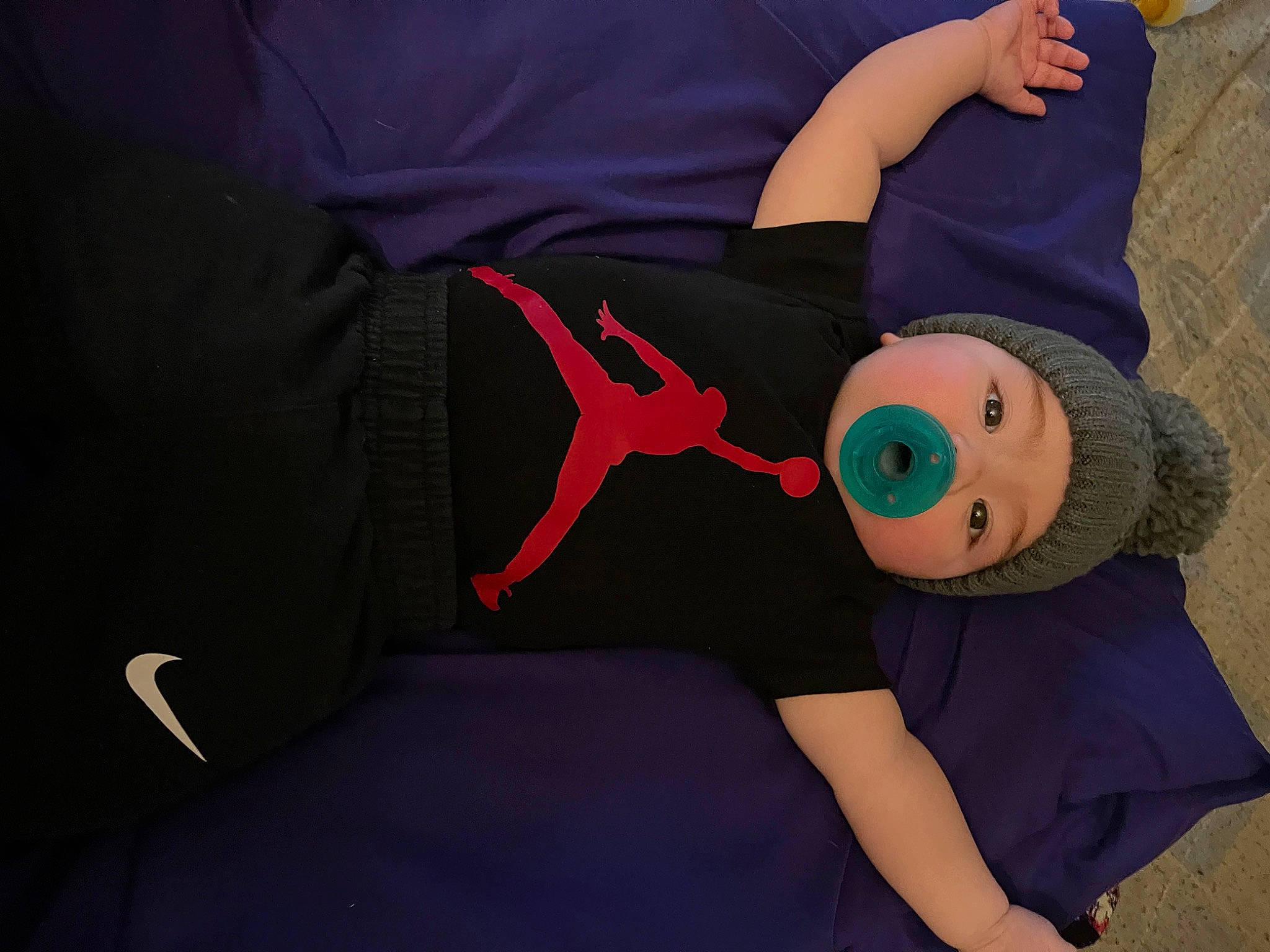 Atticus is registered to the contest to win money with this photo: baby_products, baby_toddler_clothing, child, comfort, costume_hat, elbow, gesture, hat, headwear, human_leg, knee, lap, linens, person, plush, room, sleeve, sock, t_shirt, thigh