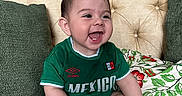 Alexander is registered to the contest to win money with this photo: baby, beige, child, comfortable, couch, cute, footwear, green_shirt, happy, home, indoor, infant, mexico, pillows, portrait, short_hair, sitting, smiling, tufted, white_shoes