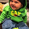 Alexander is registered to the contest to win money with this photo: toddler, child, smile, hoodie, green_clothing, hat, indoor, jeans, sitting, happy, face, baby, footwear, plush_slippers, cozy, cute, person, clothing, warm, casual