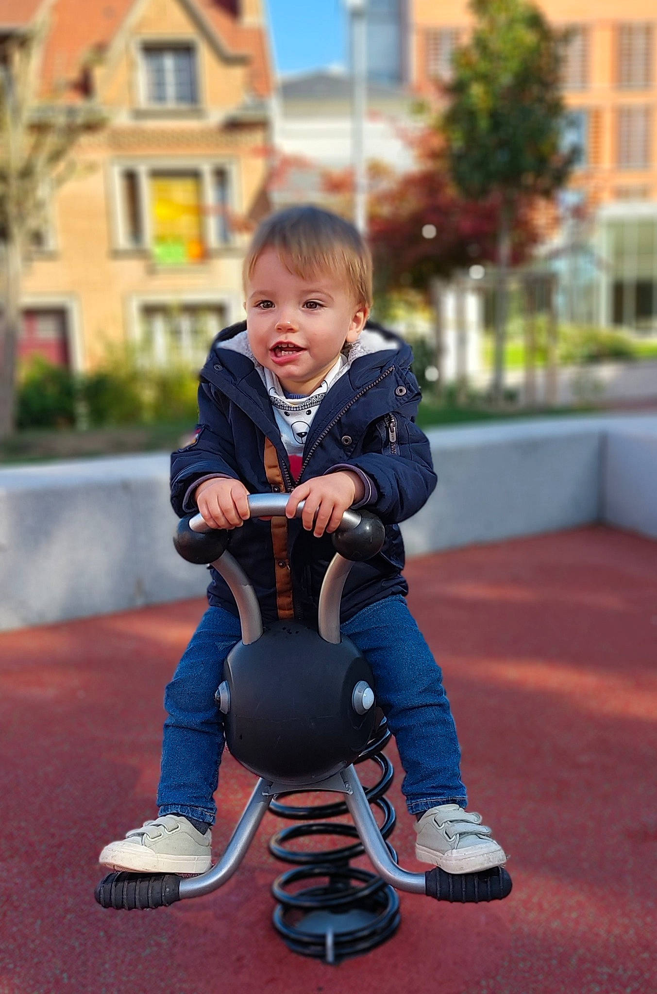 Milo participe au concours pour gagner de l'argent avec cette photo : baby, baby_toddler_clothing, child, electric_blue, eye, face, flooring, fun, grass, happy, jacket, leisure, person, plant, recreation, sitting, sleeve, smile, sneakers, toddler