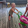 Elianna is registered to the contest to win money with this photo: toddler, toy_shopping_cart, stuffed_animals, carpet, living_room, couch, child, smiling, barefoot, person, furniture, playtime, indoor, colorful_toys, happy, home, patterned_carpet, legs, shirt, shorts