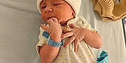 Adem participe au concours pour gagner de l'argent avec cette photo : newborn, baby, infant, hospital_bed, white_hat, onesie, blue_clothing, beige_clothing, medical_bottle, baby_wrists_band, lying_down, hand_near_mouth, soft_fabric, baby_clothes, hospital, cute, small_hands, baby_face, sleepy, cozy