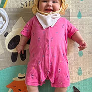 Riley joined the competition — help win amazing prizes! baby, child, colorful, cute, expression, face, hands, happy, hat, indoors, infant, legs, lying_down, pink_onesie, play_mat, skin, smiling, toy_mat, white_bib, yellow_hat