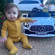 Jordan is registered to the contest to win money with this photo: baby, child, yellow_onesie, toy_car, mercedes, amg, outdoor, driveway, pebble, curious, blue_eyes, sitting, small_toy, car, vehicle, garden, plants, daylight, portrait, cute