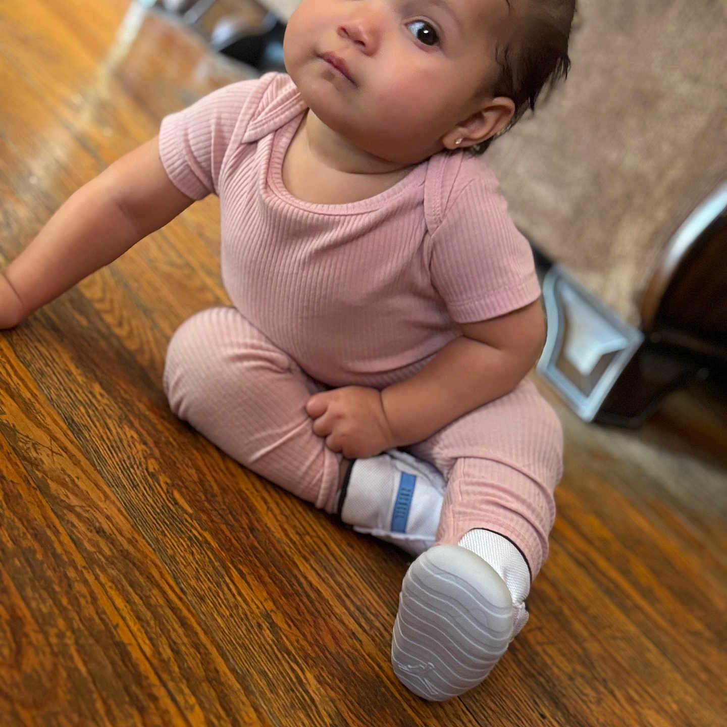 Eliani is registered to the contest to win money with this photo: adorable, baby, bow, casual_clothing, child, curious_eyes, cute, flooring, furniture, home, indoors, infant, looking_up, person, pink_outfit, portrait, sitting, small_child, white_shoes, wooden_floor