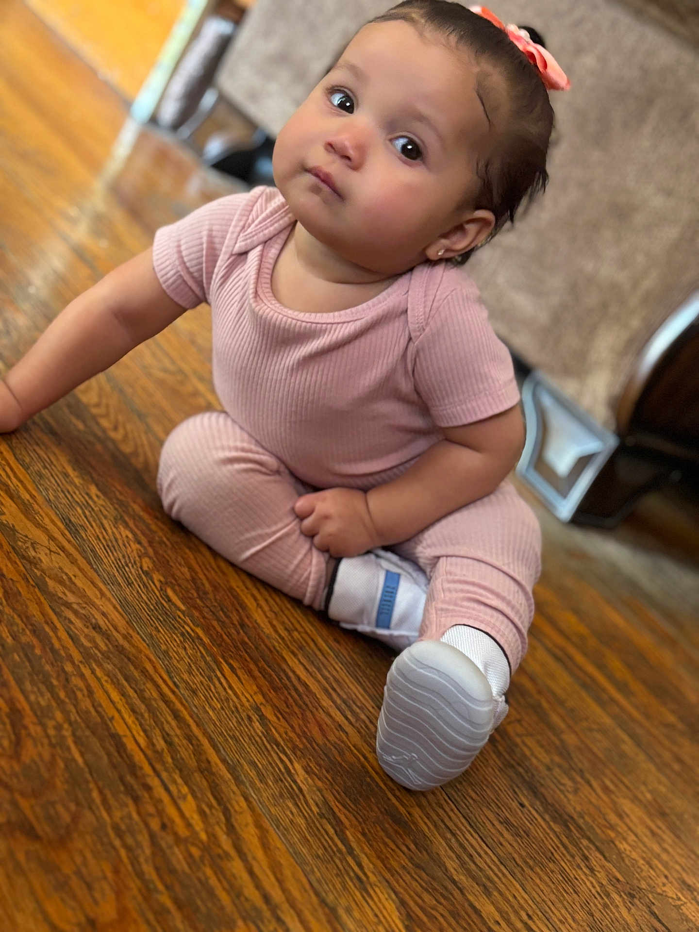Eliani is registered to the contest to win money with this photo: baby, child, pink_outfit, sitting, wooden_floor, bow, curious_eyes, white_shoes, indoors, flooring, cute, portrait, home, furniture, person, small_child, infant, casual_clothing, looking_up, adorable