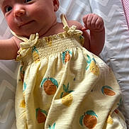 Alora joined the competition — help win amazing prizes! baby, infant, child, yellow_dress, fruit_pattern, chevron_pattern, changing_pad, cute, smiling, lying_down, clothing, fabric, skin, face, hand, head, person, indoors, soft_light, newborn