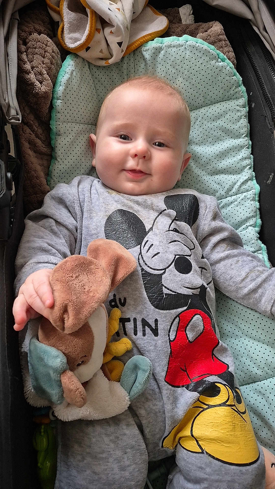 Kélyo participe au concours pour gagner de l'argent avec cette photo : baby, infant, child, smiling, stuffed_animal, plush_toy, mickey_mouse, clothing, cushion, blanket, indoor, portrait, cute, soft_toy, baby_clothes, happy, lying_down, hand, face, young_child