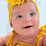 baby, smiling, yellow_headband, flower, yellow_outfit, close_up, cute, infant, happy, child, portrait, face, skin, eyes, hand, clothing, headwear, baby_girl, adorable, cheerful