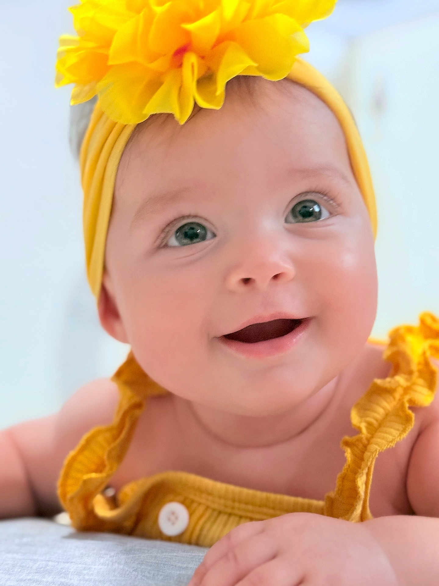 Brianna is registered to the contest to win money with this photo: baby, smiling, yellow_headband, flower, yellow_outfit, close_up, cute, infant, happy, child, portrait, face, skin, eyes, hand, clothing, headwear, baby_girl, adorable, cheerful