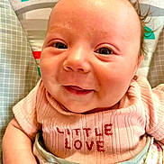 Arizona joined the competition — help win amazing prizes! baby, smiling, infant, pink_clothing, face, cute, happy, child, portrait, closeup, sitting, apparel, text_on_clothing, indoor, colorful_background, young_child, skin, head, eyes, person
