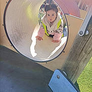 Azra is registered to the contest to win money with this photo: child, curious, cute, daytime, fun, grass, handrail, jacket, leopard_print, outdoor, play, playground, slide, sunlight, toddler, tunnel, vest, winter_clothing, wood, young_child