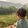 child, toddler, rain, outdoor, greenery, grass, trees, mountain, nature, curly_hair, barefoot, pacifier_clip, shirt, side_view, sitting, stone_ledge, peaceful, calm, landscape, cloudy