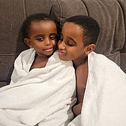 James is registered to the contest to win money with this photo: child, children, towel, white_towel, couch, brown_couch, indoor, portrait, smile, affection, siblings, close, wrapped, cozy, cute, happy, toddler, young, family, love