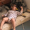 toddler, dog, sleeping, mattress, floor, pacifier, heart_pattern, onesie, indoor, cabinet, books, fluffy_dog, resting, friendship, cozy, barefoot, protective, quiet, relaxed, calm