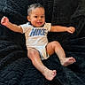 baby, child, smiling, happy, nike, onesie, infant, sitting, black_blanket, cozy, cute, portrait, baby_boy, barefoot, indoor, young_child, playful, expression, clothing, relaxed