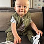 toddler, child, baby, sitting, couch, shoe, sneaker, green_vest, striped_shirt, indoor, smile, face, hand, footwear, person, home, furniture, cute, young_child, blond_hair