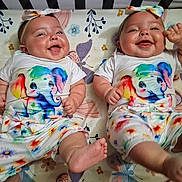 Juanita And Regina joined the competition — help win amazing prizes! baby, twins, infant, smiling, lying_down, headband, colorful_clothing, elephant_print, floral_pattern, cute, happy, chubby, indoors, crib, person, toddler, playful, joyful, apparel, portrait