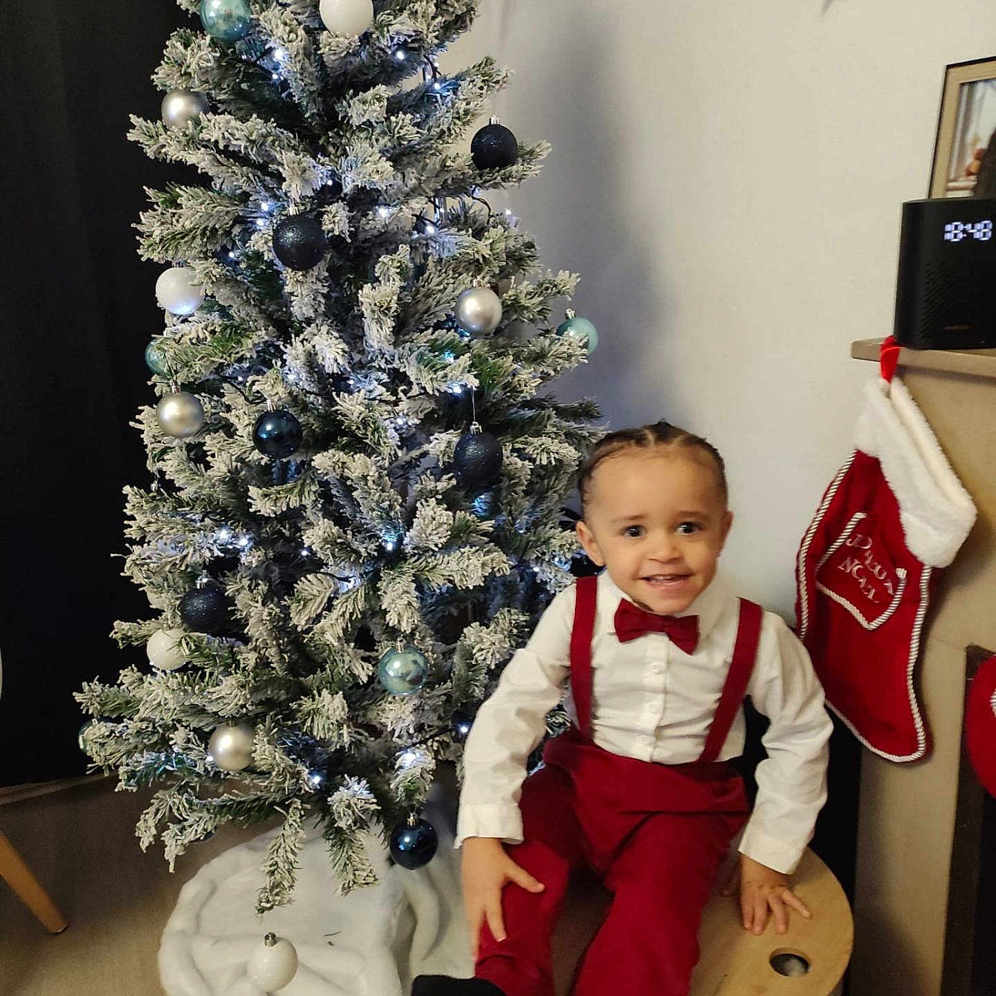 Loenn participe au concours pour gagner de l'argent avec cette photo : baby, christmas, christmasdecorations, clothing, face, festival, footwear, furniture, head, lighting, pants, person, photography, plant, portrait, pottedplant, shoe, sitting, table, tree