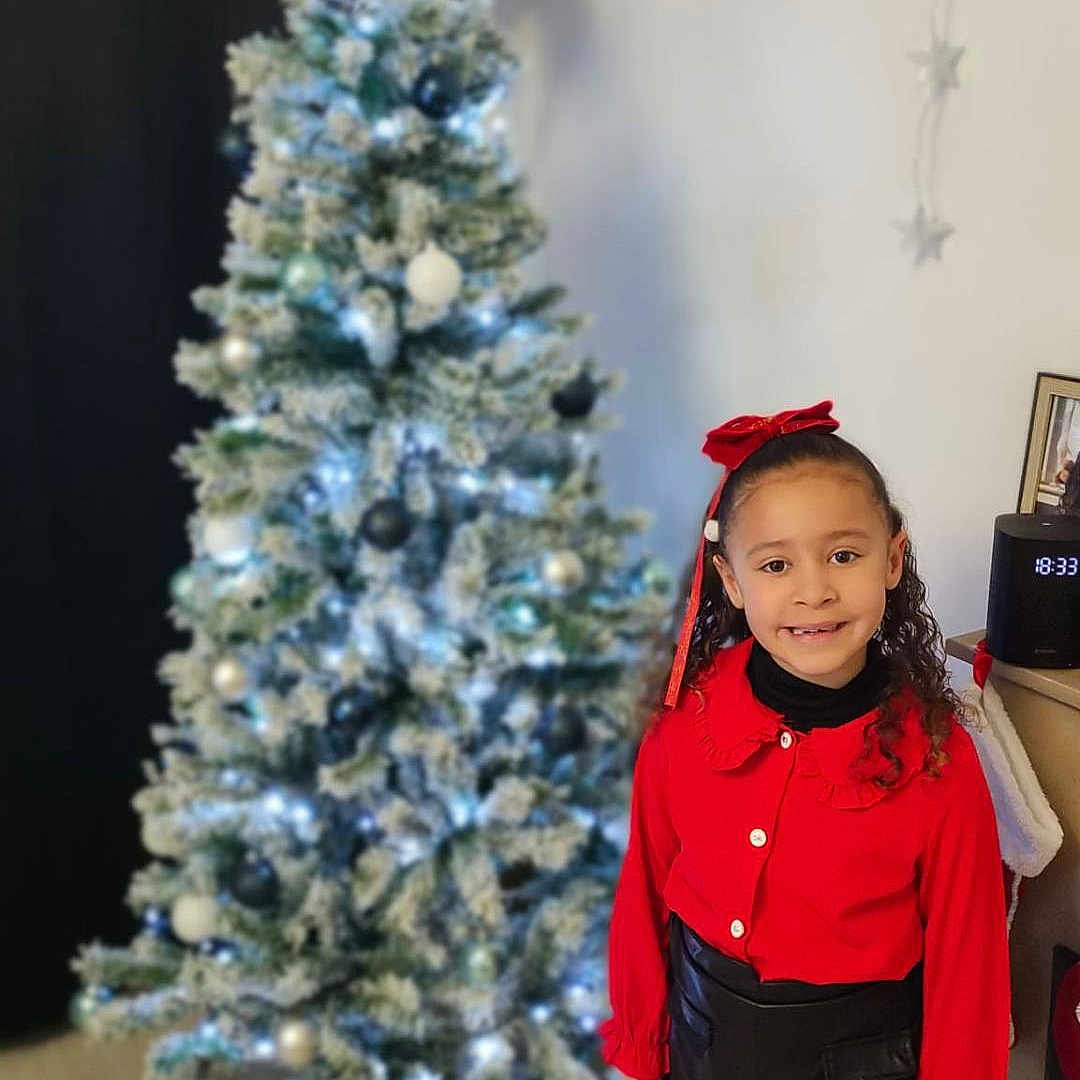 Laïly a rejoint le concours — aidez-le/la à gagner de superbes lots ! accessories, child, christmas, christmasdecorations, christmastree, clothing, coat, face, female, festival, girl, head, jacket, pants, person, photography, plant, portrait, sleeve, tree