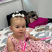 Allysson joined the competition — help win amazing prizes! baby, child, pink_dress, heart_pattern, headband, curly_hair, bed, blanket, toy, indoor, shoes, bag, curtain, person, cute, sitting, holding, foot, smiling, portrait