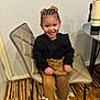 child, girl, smiling, braided_hair, bows, black_top, mustard_tights, black_boots, chair, indoor, floor, table, carpet, happy, portrait, person, seated, fashion, cute, young
