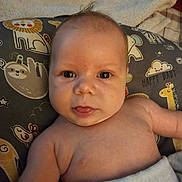 Ethan is registered to the contest to win money with this photo: baby, infant, face, tongue, blanket, pillow, animal_print, lion, giraffe, elephant, sloth, smile, skin, head, eyes, cute, indoors, child, young, person