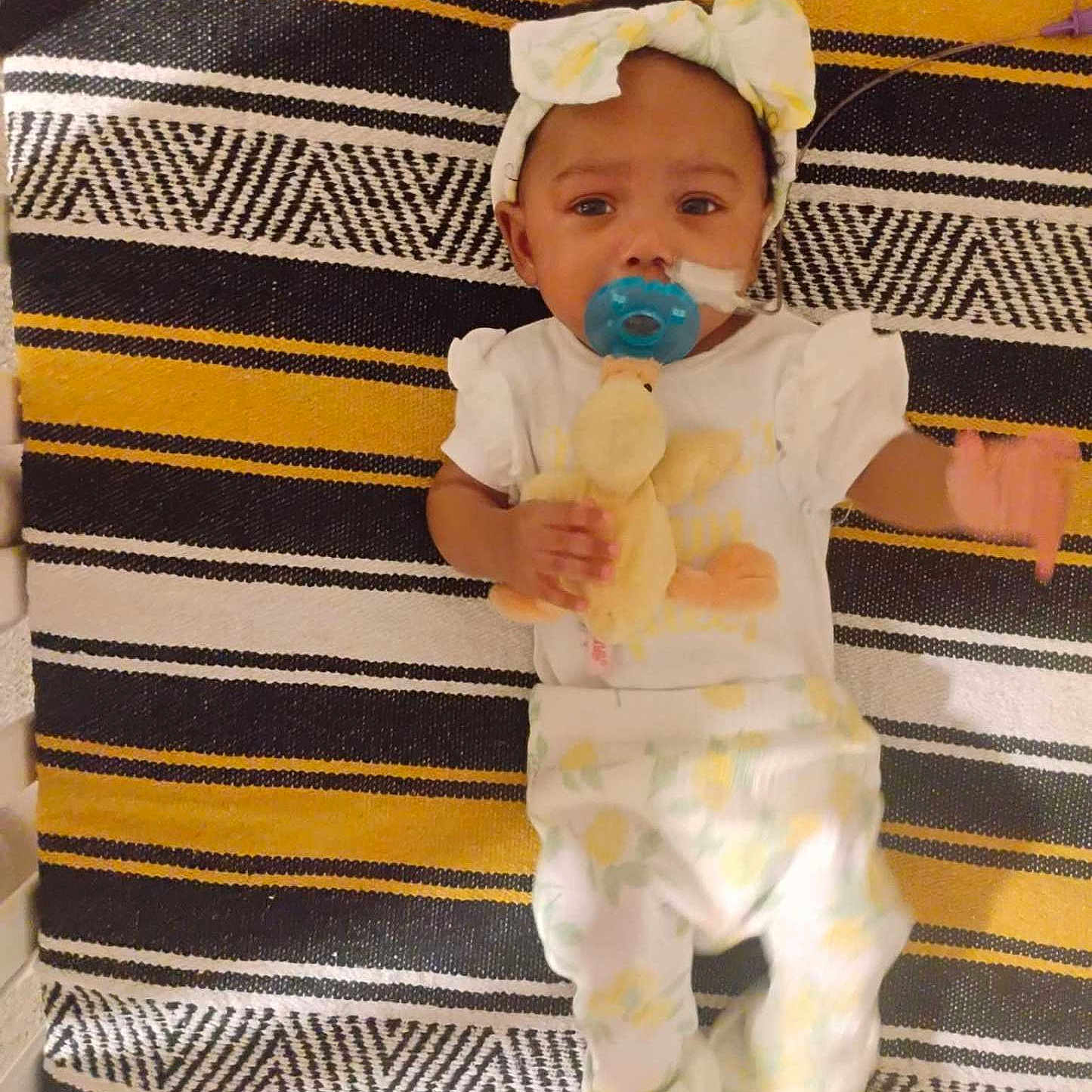 A'Millioán is registered to the contest to win money with this photo: adorable, baby, bow, child, clothing, comfort, cute, duck, headband, indoors, infant, lying_down, pacifier, pajamas, plush_toy, portrait, resting, soft_toy, striped_blanket, young_child