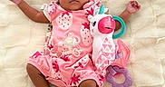 Lauryn is registered to the contest to win money with this photo: baby, infant, pink_clothing, headband, bow, unicorn_toy, plush_toy, blanket, lying_down, cute, soft_texture, child, newborn, sock, portrait, indoors, adorable, colorful, playful, resting