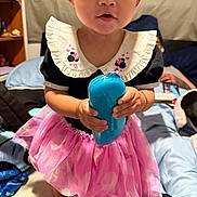 Anastasia is registered to the contest to win money with this photo: barefoot, bed, black_top, blanket, blue_object, child, clothing, dog, expression, eyes, face, furniture, hand, indoor, minnie_mouse, person, pillow, pink_tutu, room, toddler
