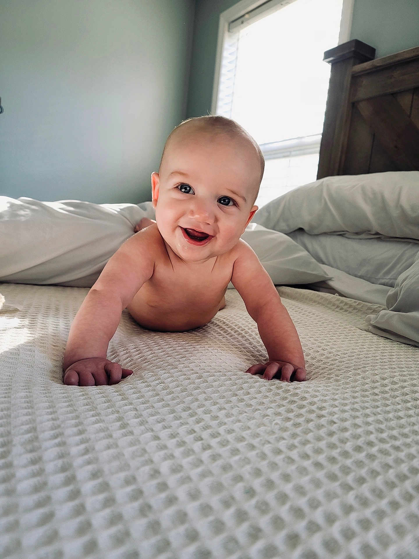 Myles joined the competition — help win amazing prizes! baby, smiling, crawling, bed, pillows, window, natural_light, wooden_headboard, indoors, child, face, happy, skin, blanket, furniture, infant, expression, room, cute, person