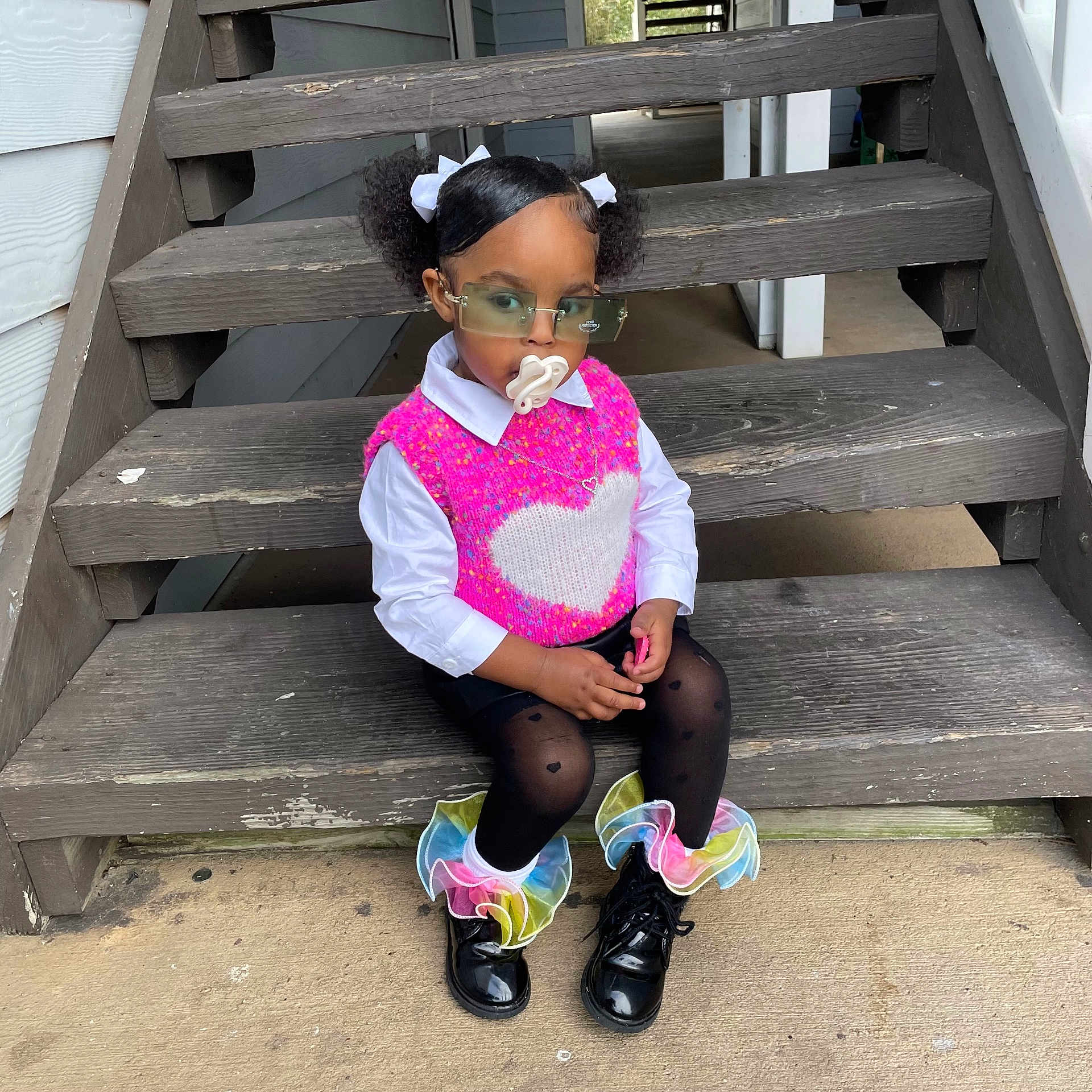 Ahlea is registered to the contest to win money with this photo: accessories, black_tights, boots, child, concrete_floor, cute, fashion, glasses, hair_puffs, heart_pattern, outdoor, pacifier, pink_vest, portrait, ruffles, sitting, stairs, toddler, white_bows, wooden_stairs