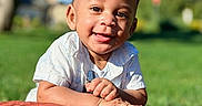 Issac is registered to the contest to win money with this photo: baby, child, smiling, outdoor, grass, blanket, sunlight, portrait, happy, nature, greenery, face, infant, cute, person, blue_sky, short_hair, white_shirt, daylight, warm