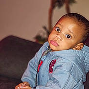 Issac joined the competition — help win amazing prizes! child, toddler, hoodie, blue_clothing, indoor, couch, furniture, hands, face, curious_expression, person, young_child, casual_wear, home_interior, seated, portrait, brown_skin, short_hair, cute, baby