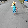 Cambrie is registered to the contest to win money with this photo: child, street, hat, dress, walking, plastic_bag, road, footwear, summer, outdoor, nature, casual, back_view, person, daytime, greenery, sidewalk, blue, pattern, rural