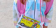 Cambrie is registered to the contest to win money with this photo: child, sidewalk, backpack, school, tie_dye, hoodie, sneakers, smile, person, outdoor, concrete, bus_sign, young, cute, holding, casual, clothing, feet, portrait, daytime