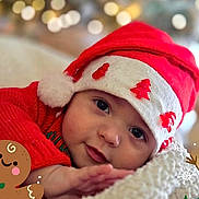 Arthur participe au concours pour gagner de l'argent avec cette photo : baby, infant, christmas_hat, red_clothing, holiday, festive, face, cute, smiling, indoors, soft_blanket, decorations, cartoon_gingerbread, cartoon_snowman, winter, closeup, portrait, holiday_season, celebration, child