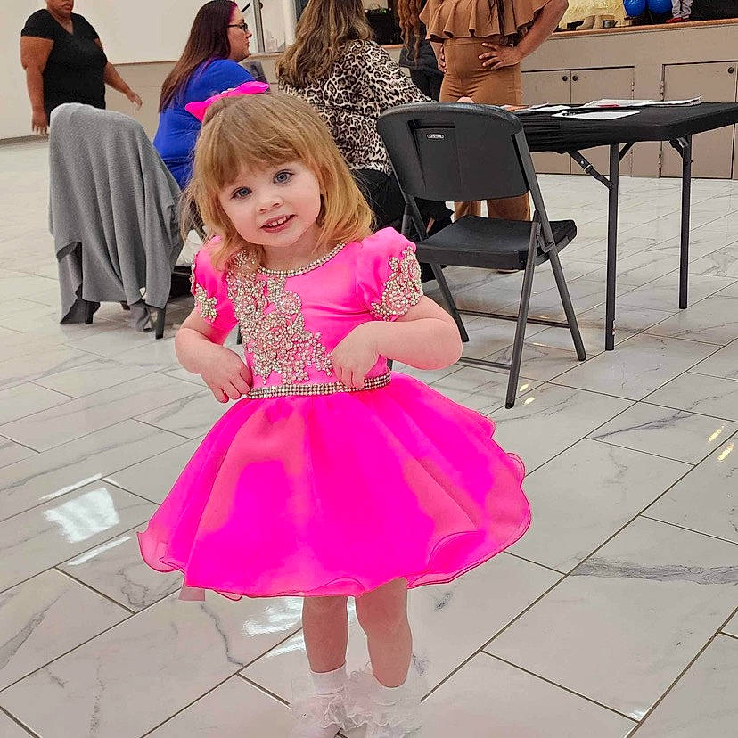 Rhythm is registered to the contest to win money with this photo: baby_toddler_clothing, chair, child, clothing, dress, event, floor, flooring, fun, happy, joint, joy, leg, magenta, person, pink, purple, skin, sleeve, smile